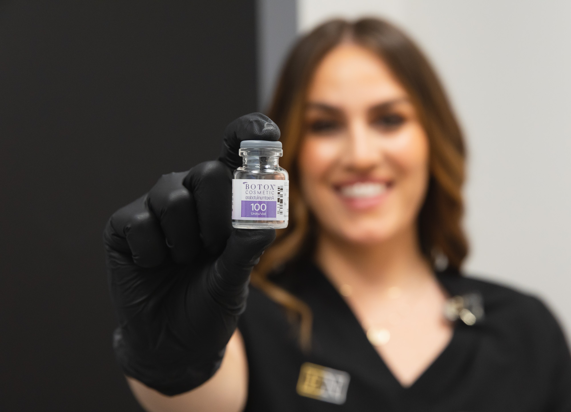 woman holding a bottle of Botox close to the camera
